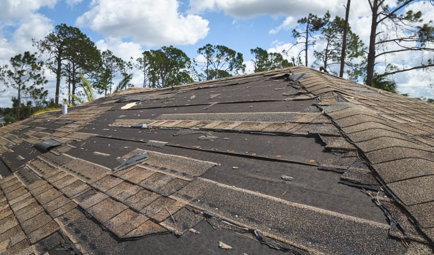 Damaged house roof with missing shingles after hurricane Ian in Florida. Consequences of natural disaster.