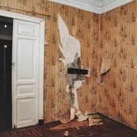 Background of old interior of an abandoned communal apartment, dirty room, rotten peeling walls. Old Soviet Russian past of poor interior. Scuffed floor. Stripped wallpaper on the wall. Repair concept
